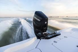 Boat speeding across calm water, leaving a white wake behind a black outboard motor at sunset.