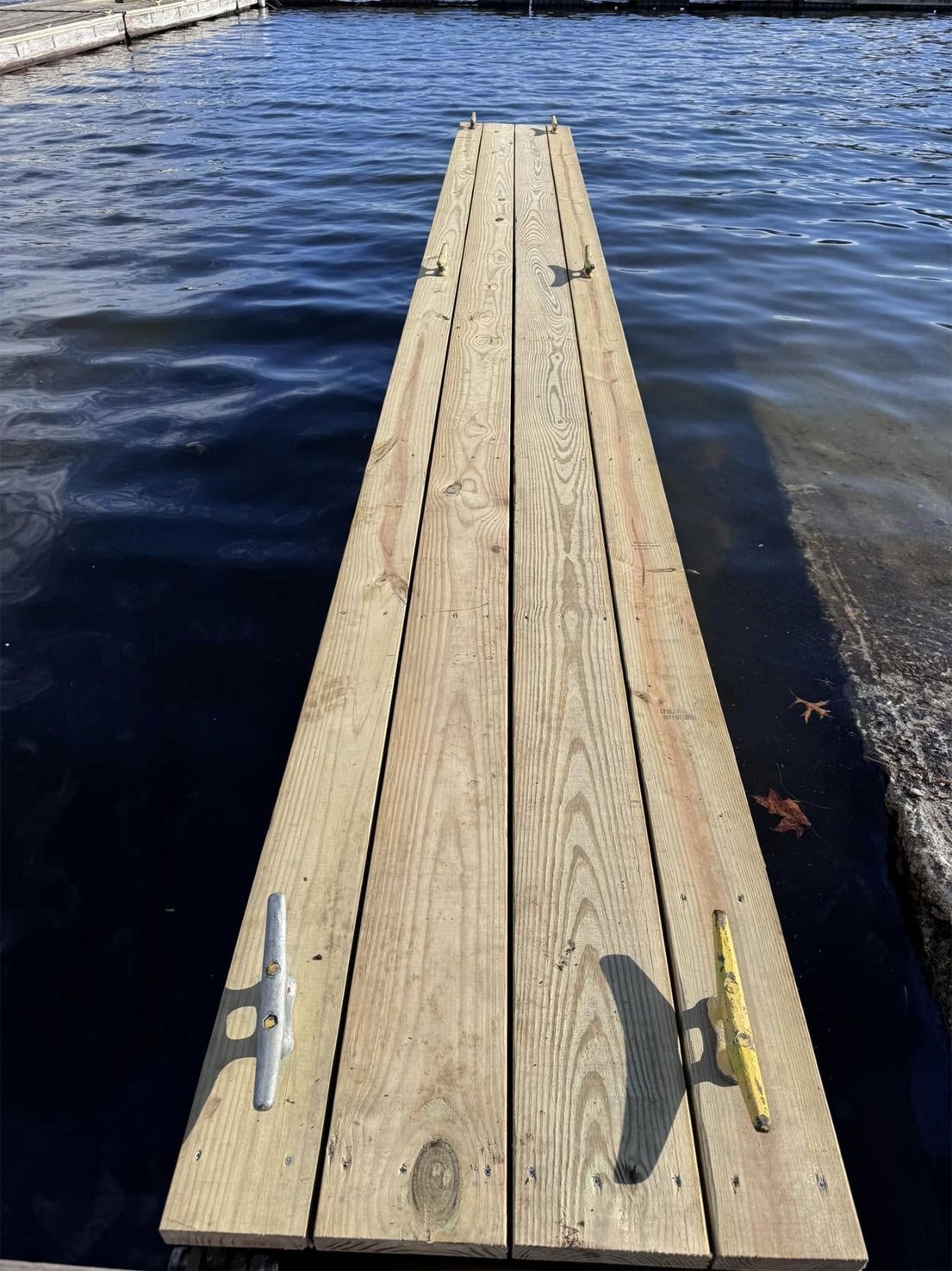 Wooden dock extending into rippling blue water under clear daylight.