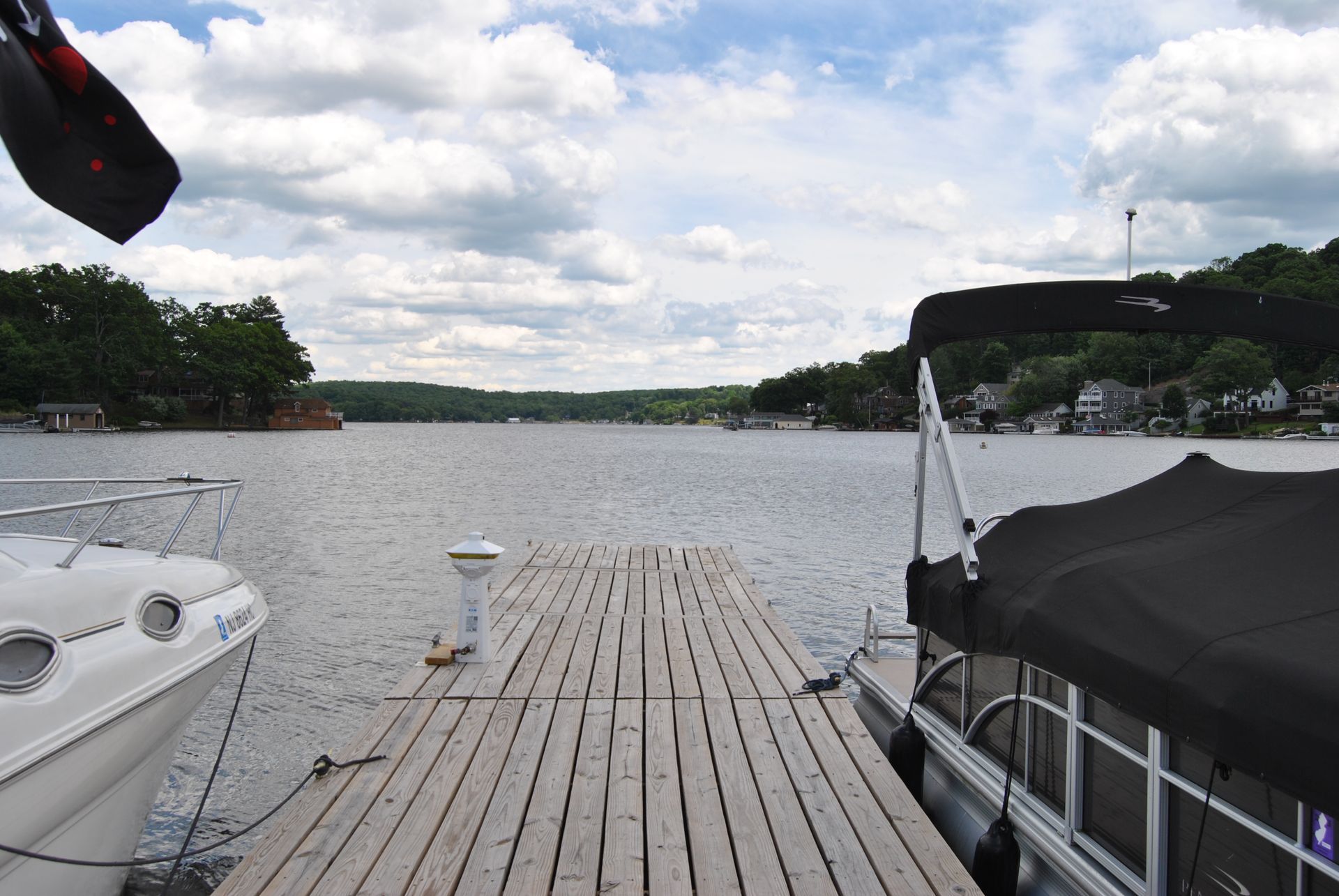 Dock leading to a calm lake with boats on both sides under a cloudy sky