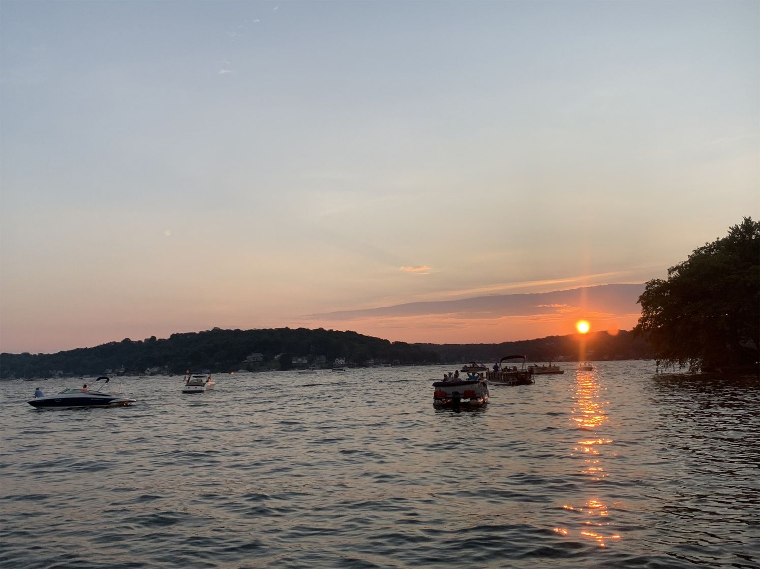 Sunset over a calm harbor with boats silhouetted on the water and a glowing reflection on the waves