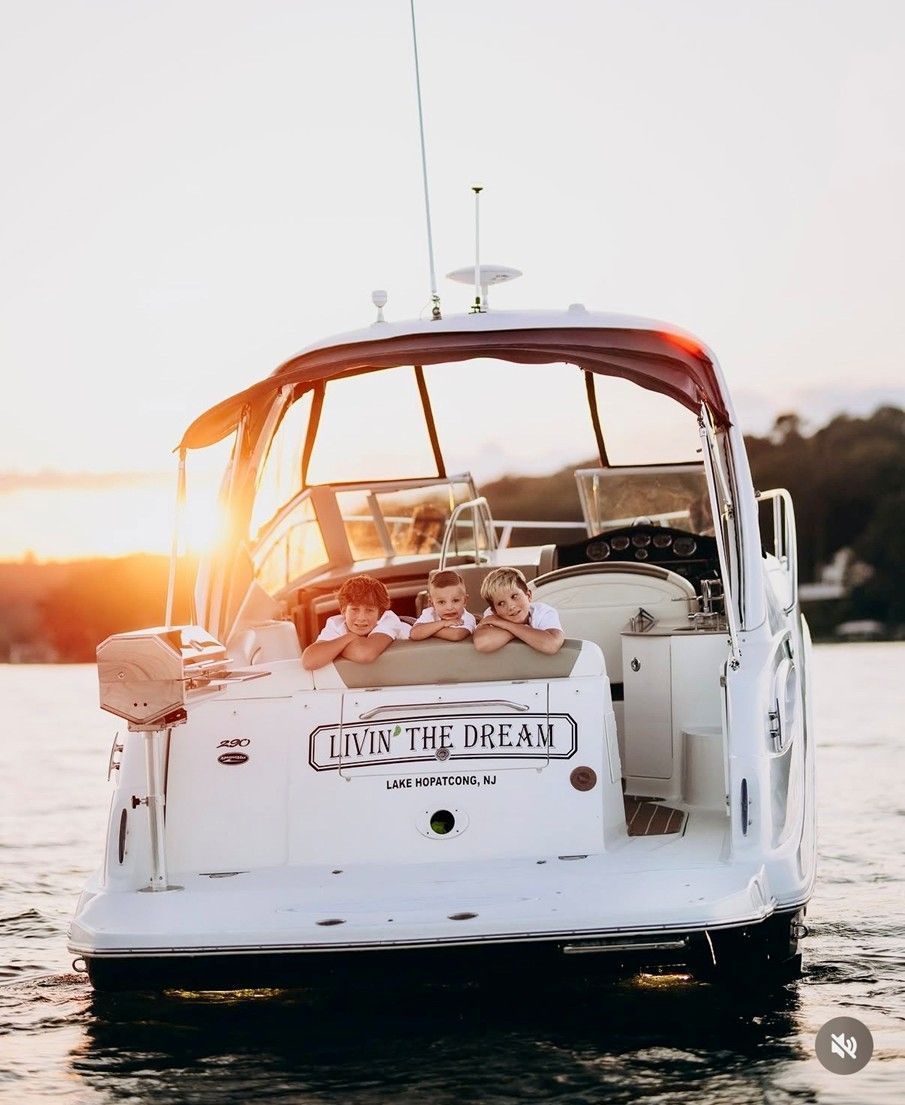 White sailboat at sunset with people relaxing on deck on calm water