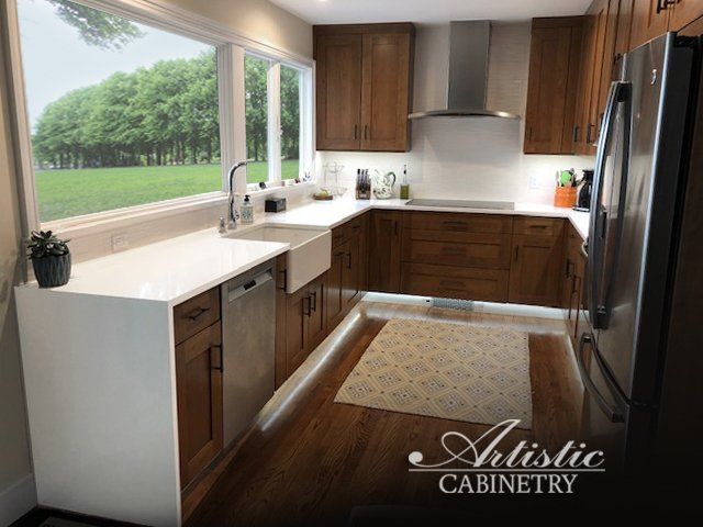 A kitchen with wooden cabinets and stainless steel appliances from artistic cabinetry