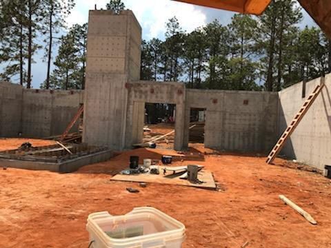 A bucket of paint is sitting on the ground in front of a building under construction.