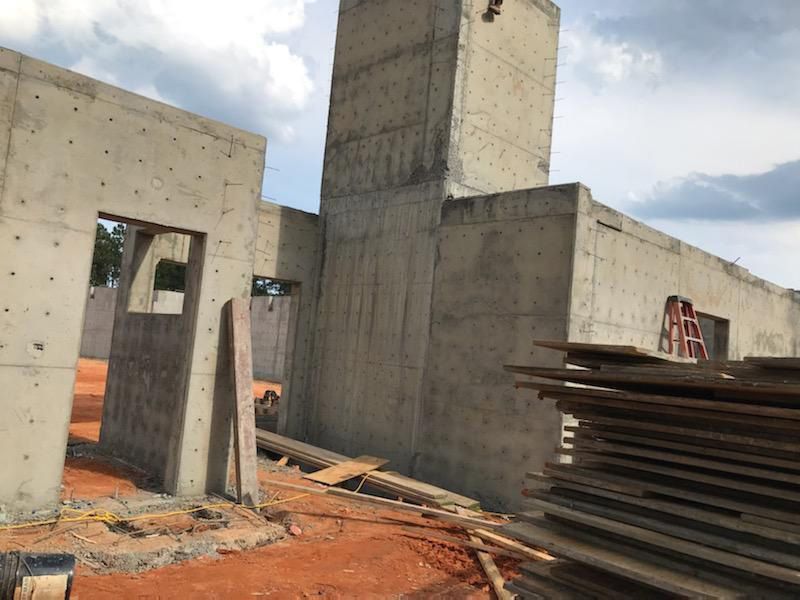 A building under construction with a stack of wood in front of it.