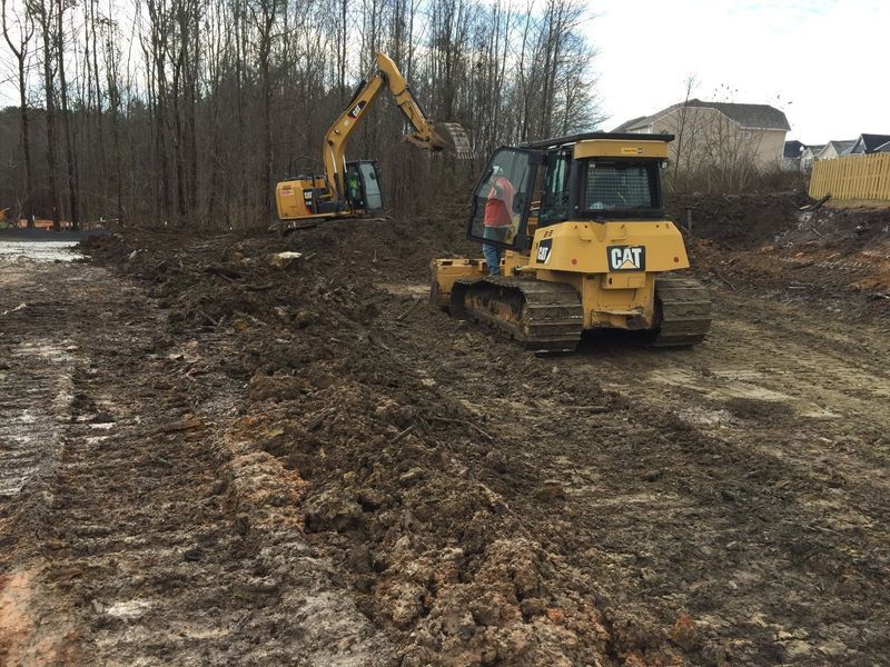 A bulldozer and an excavator are working on a dirt road.
