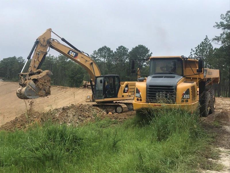 A bulldozer and a dump truck are working on a dirt road.