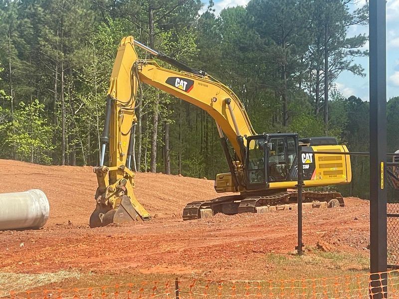 A large yellow excavator is working on a dirt field.