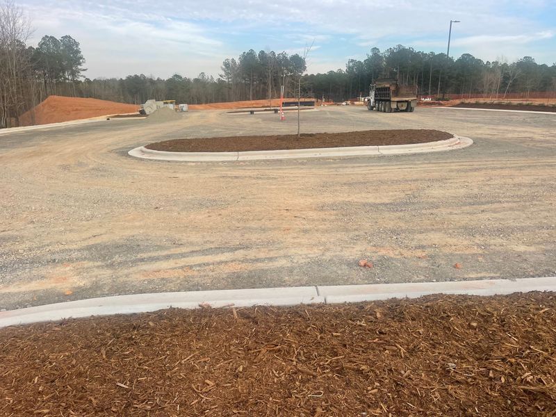 A construction site with a lot of dirt and trees in the background.