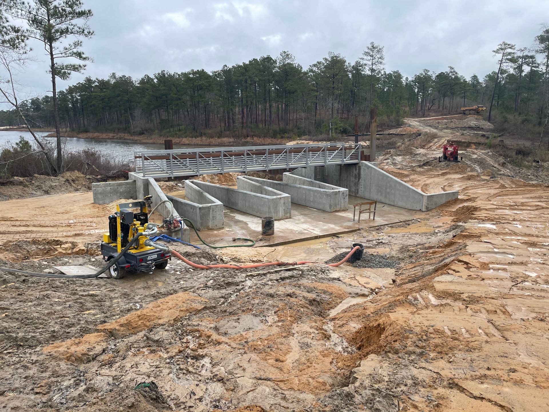 A small yellow excavator is sitting in the middle of a dirt field.
