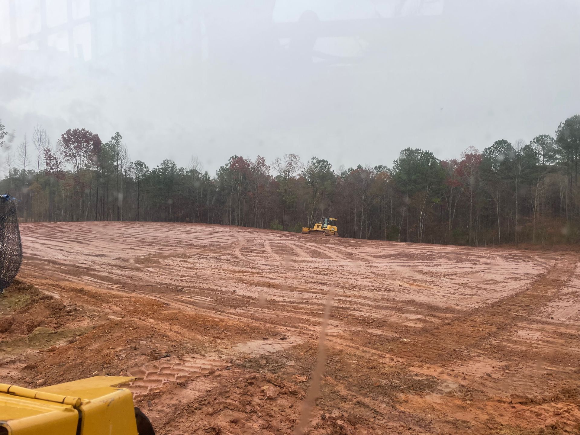 A yellow tractor is driving through a muddy field.