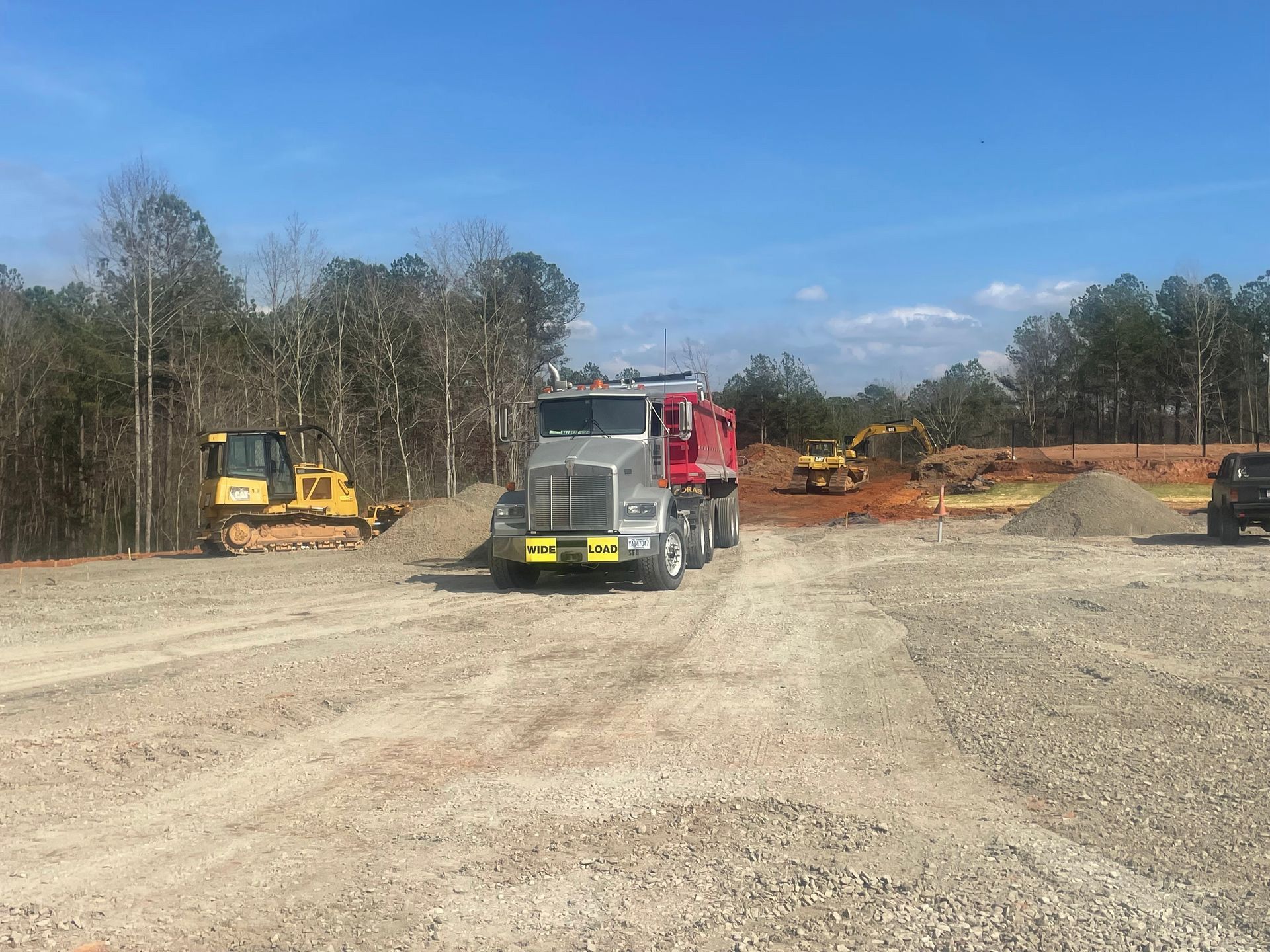 A dump truck is driving down a dirt road in a construction site.