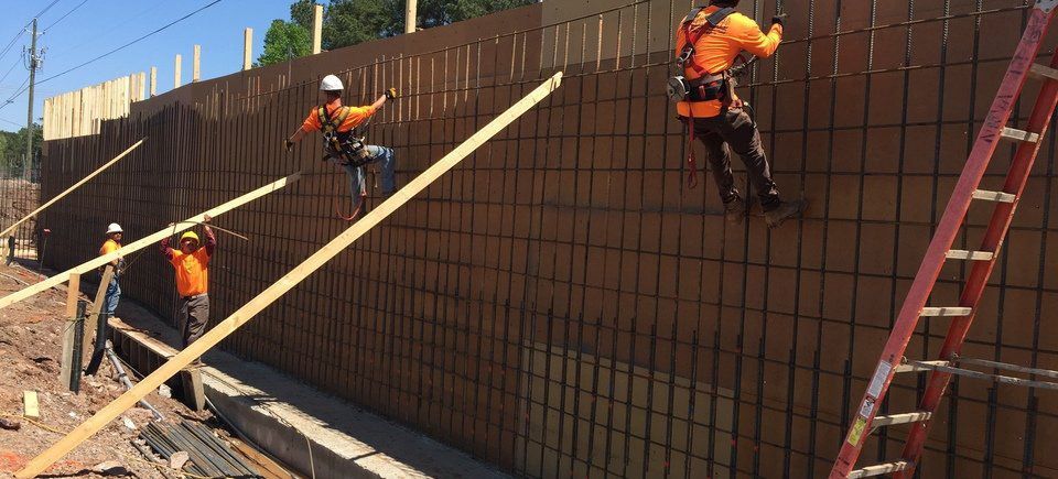 A group of construction workers are working on a concrete wall.