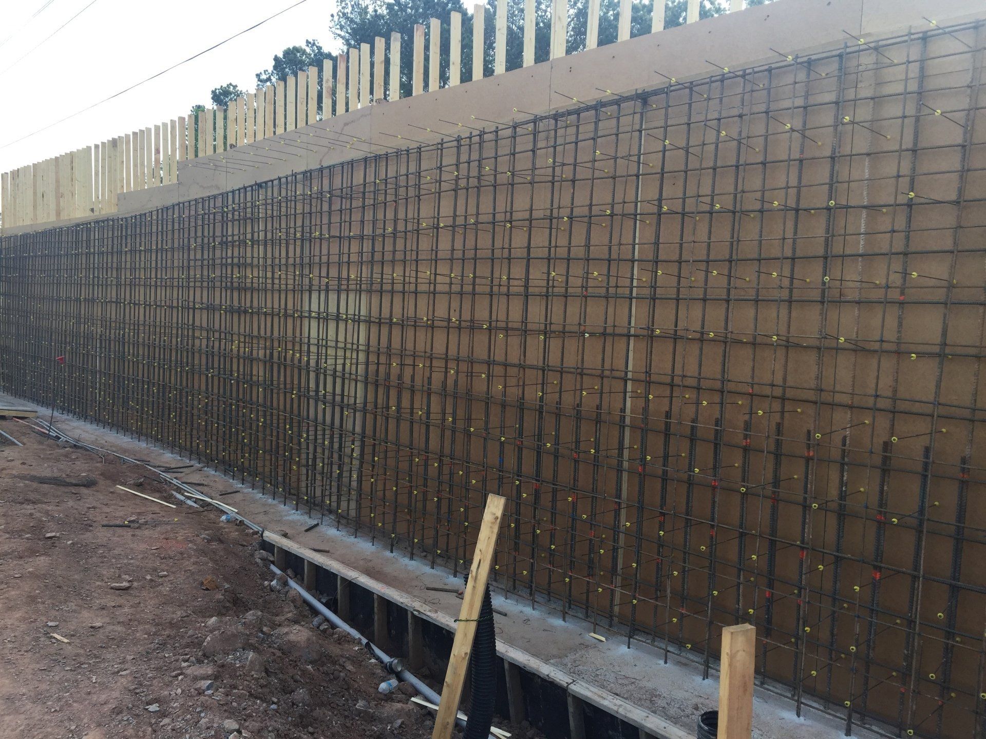 A large wall is being built with a fence in the background.