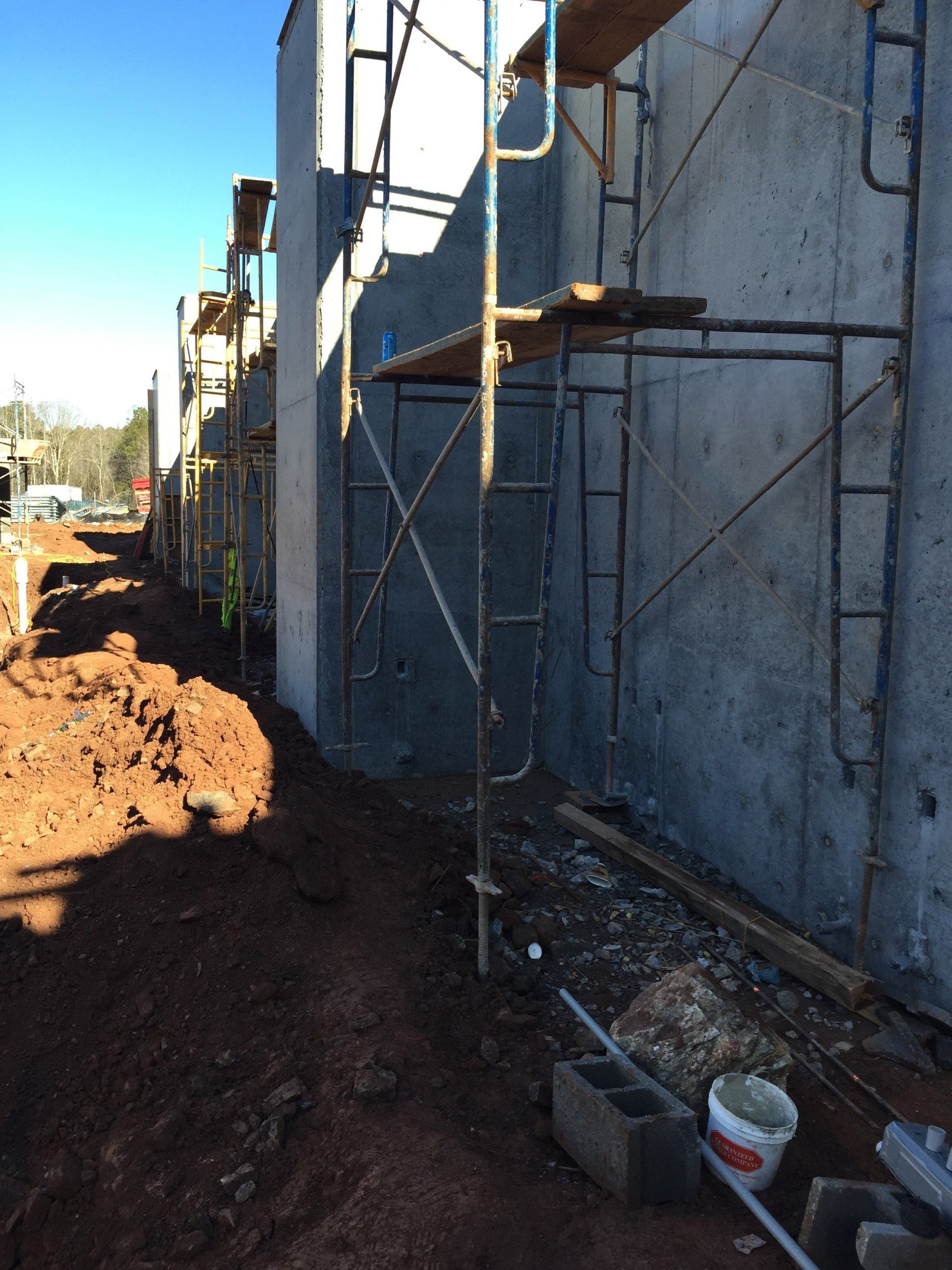 A construction site with scaffolding and a bucket of paint.