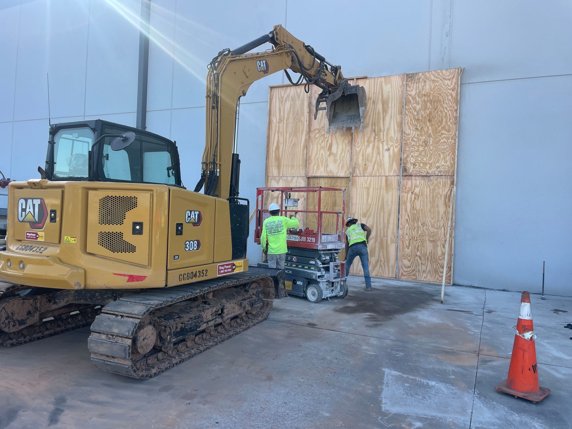 A cat excavator is being used to board up a building.
