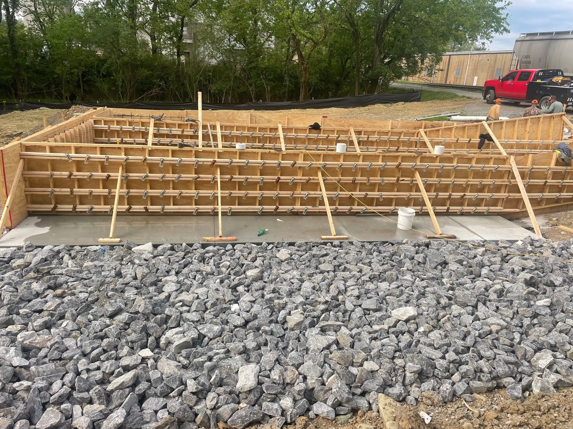 A construction site with a lot of rocks and a red truck in the background.