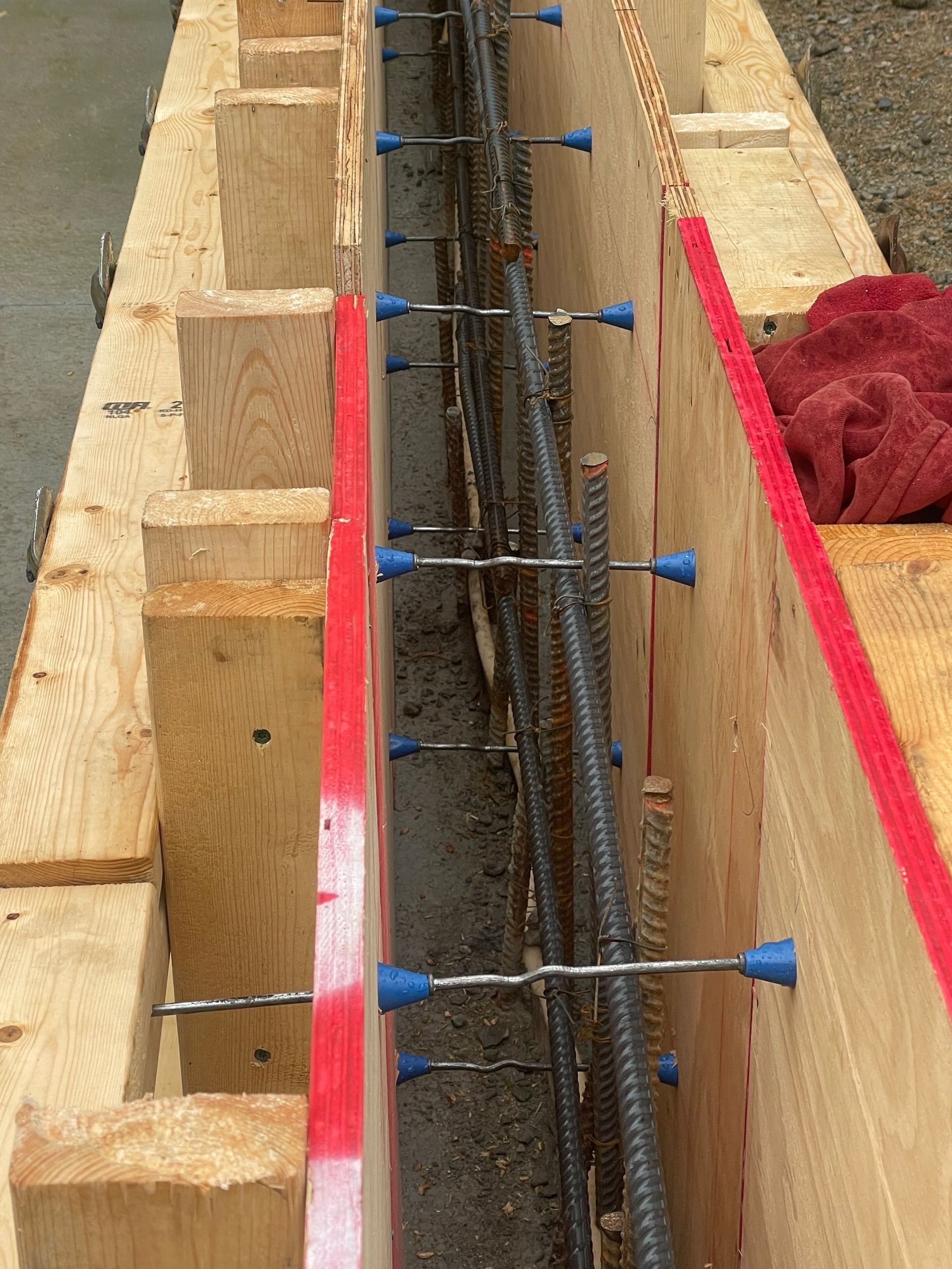 A wooden wall with blue screws and a red stripe on it is being built.