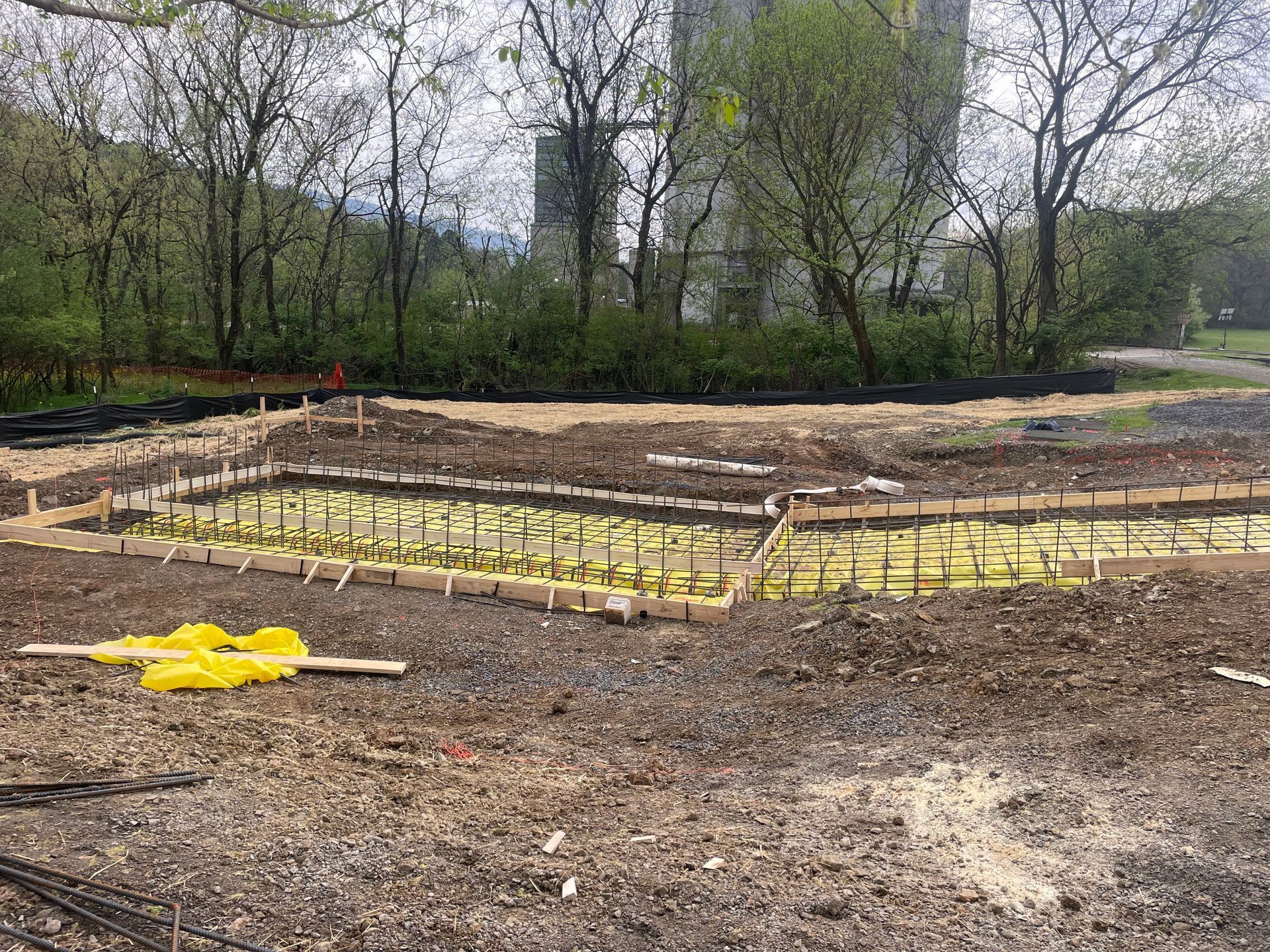 A construction site with a lot of dirt and trees in the background.