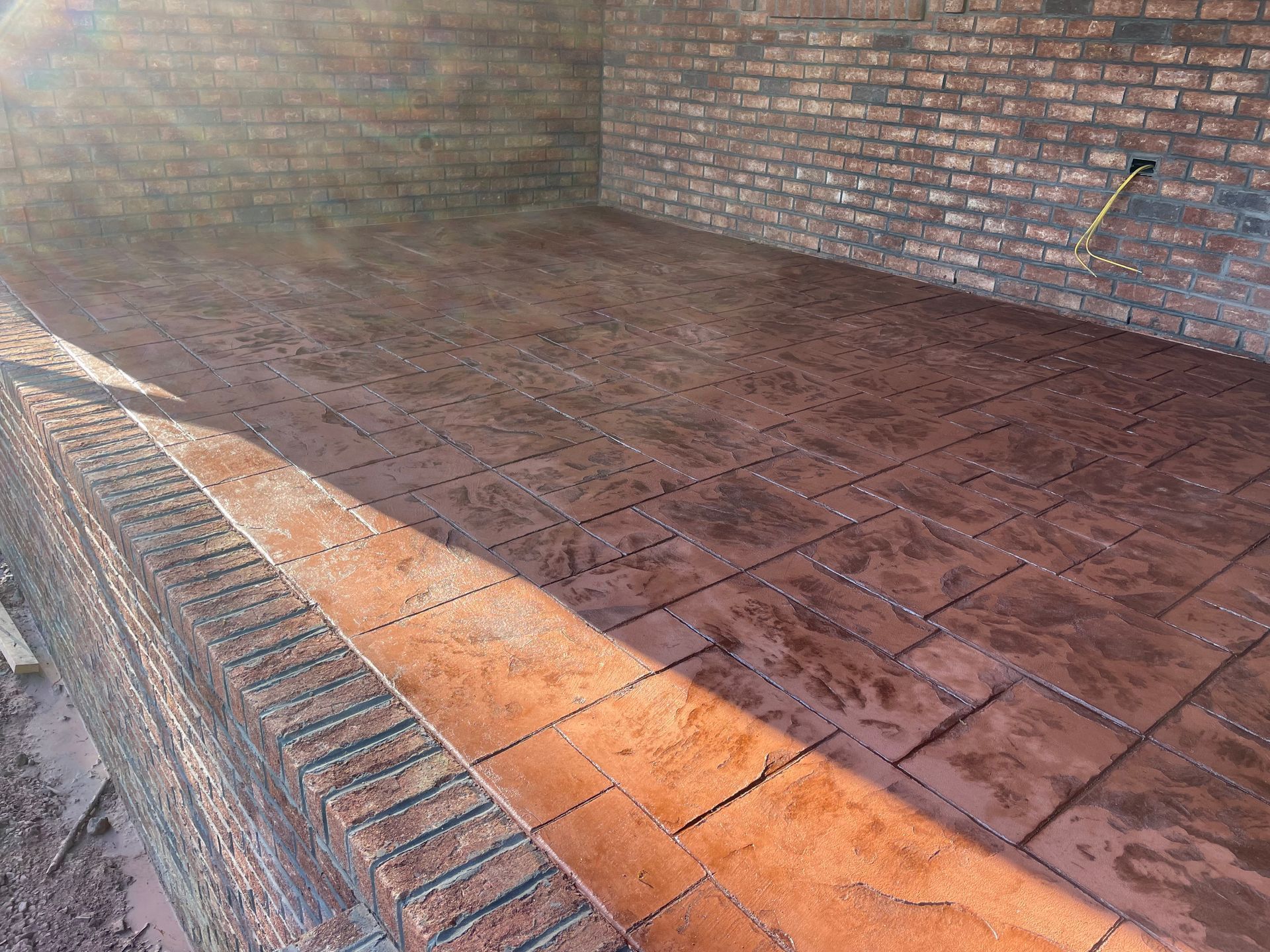 A brick wall with a concrete floor in front of it.