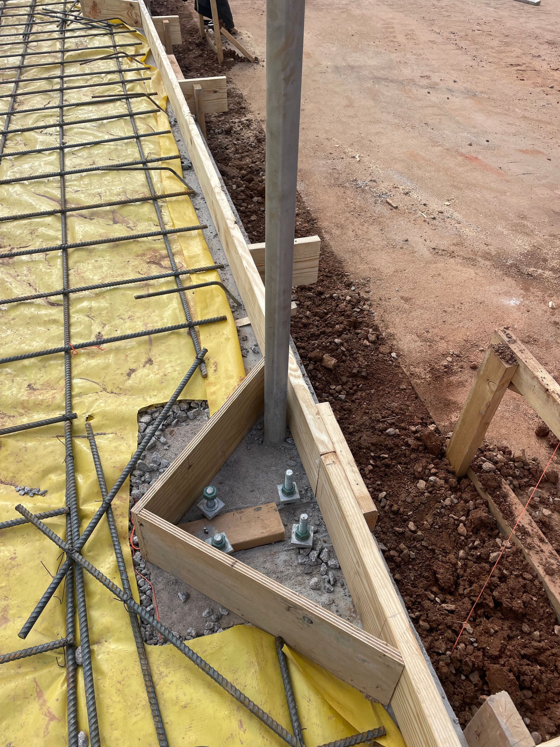 A metal pole is sitting in the middle of a construction site.