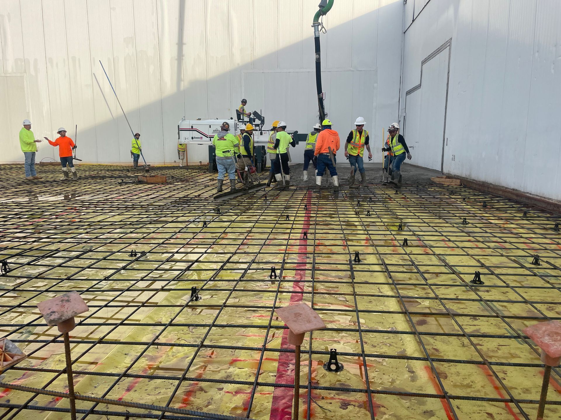 A group of construction workers are working on a concrete floor.