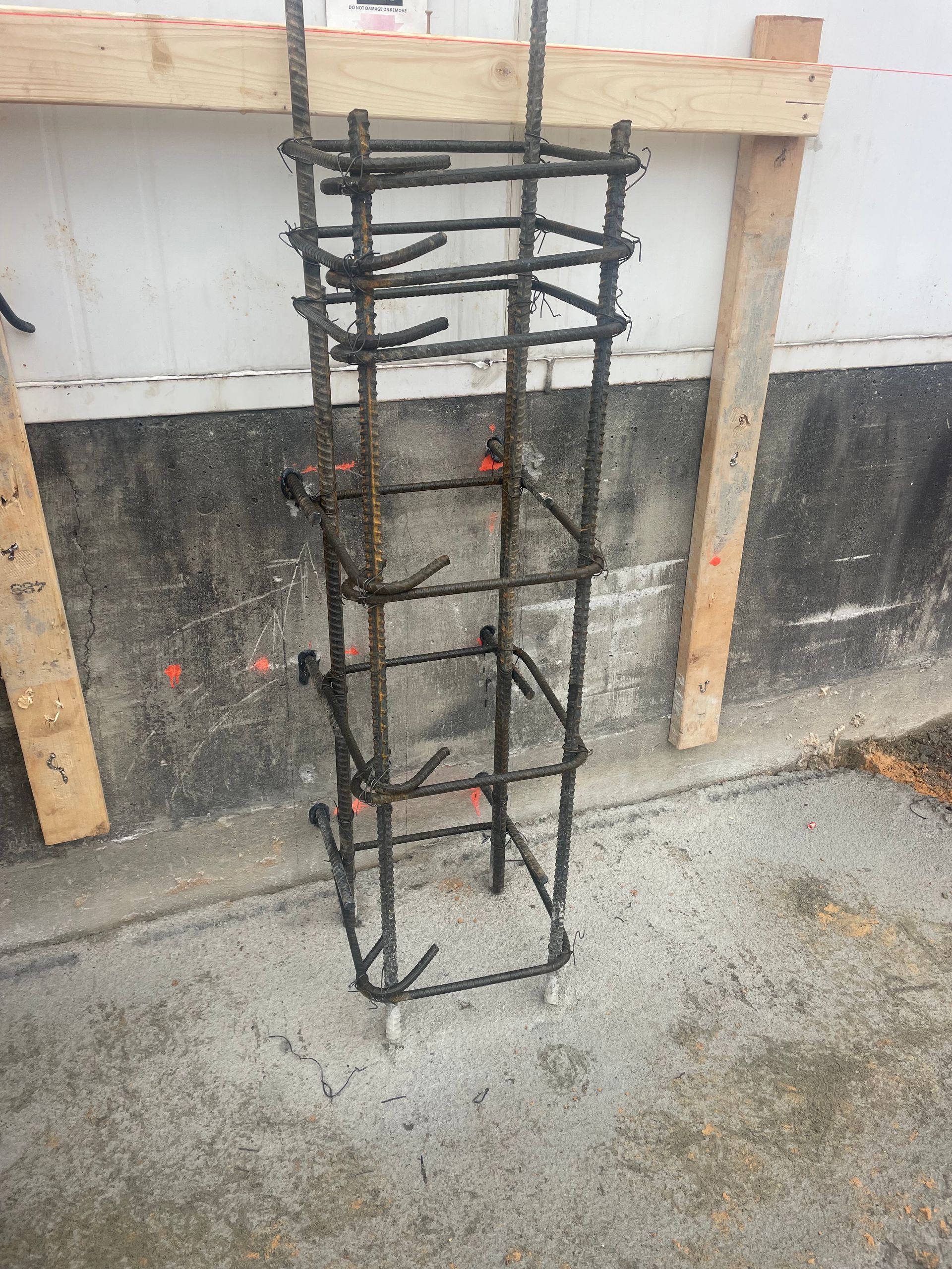 A metal structure is sitting on the ground in front of a wall.