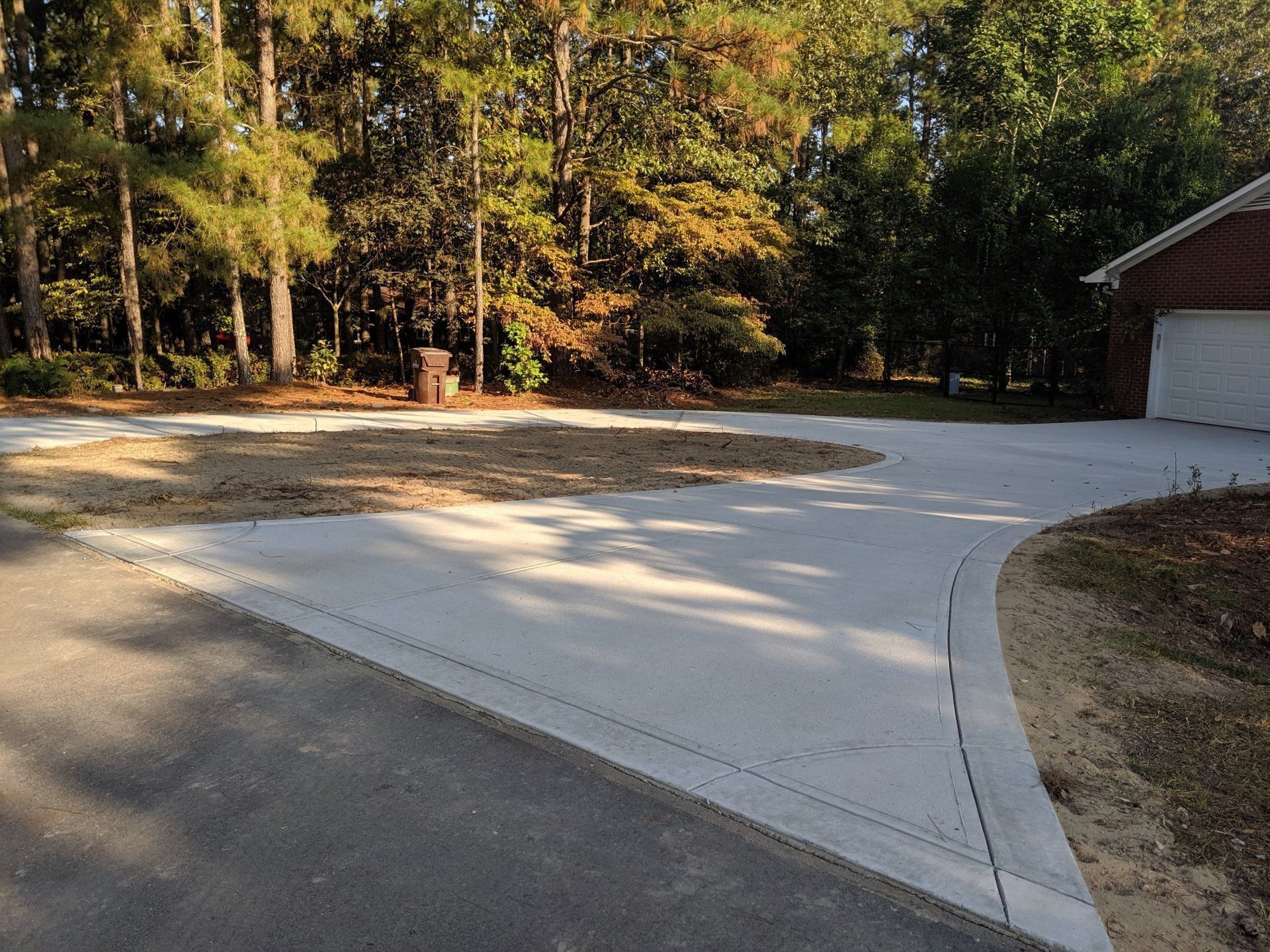 A concrete driveway leading to a garage with trees in the background