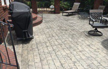 A patio with a grill and chairs on it.