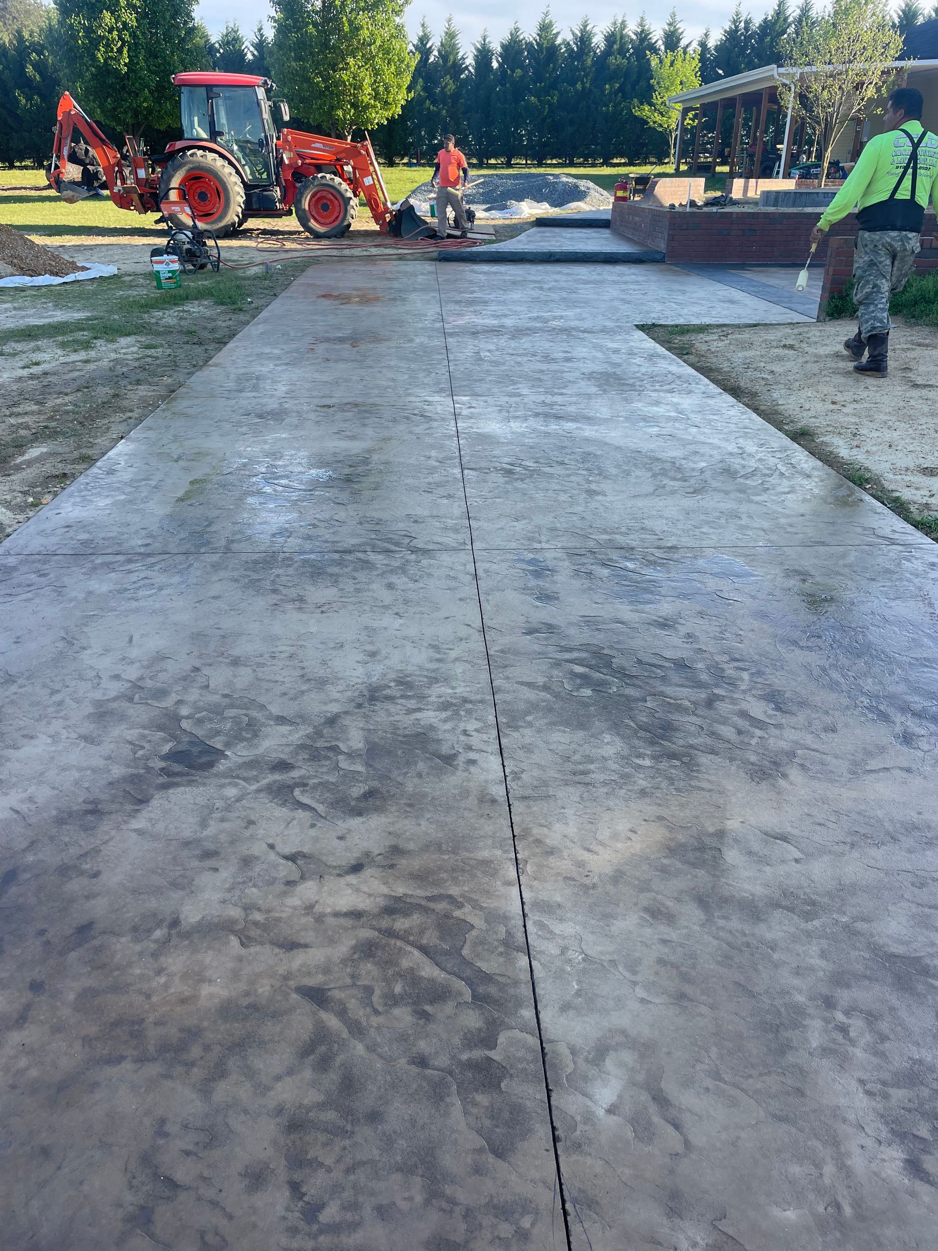 A tractor is parked on the side of a concrete driveway.