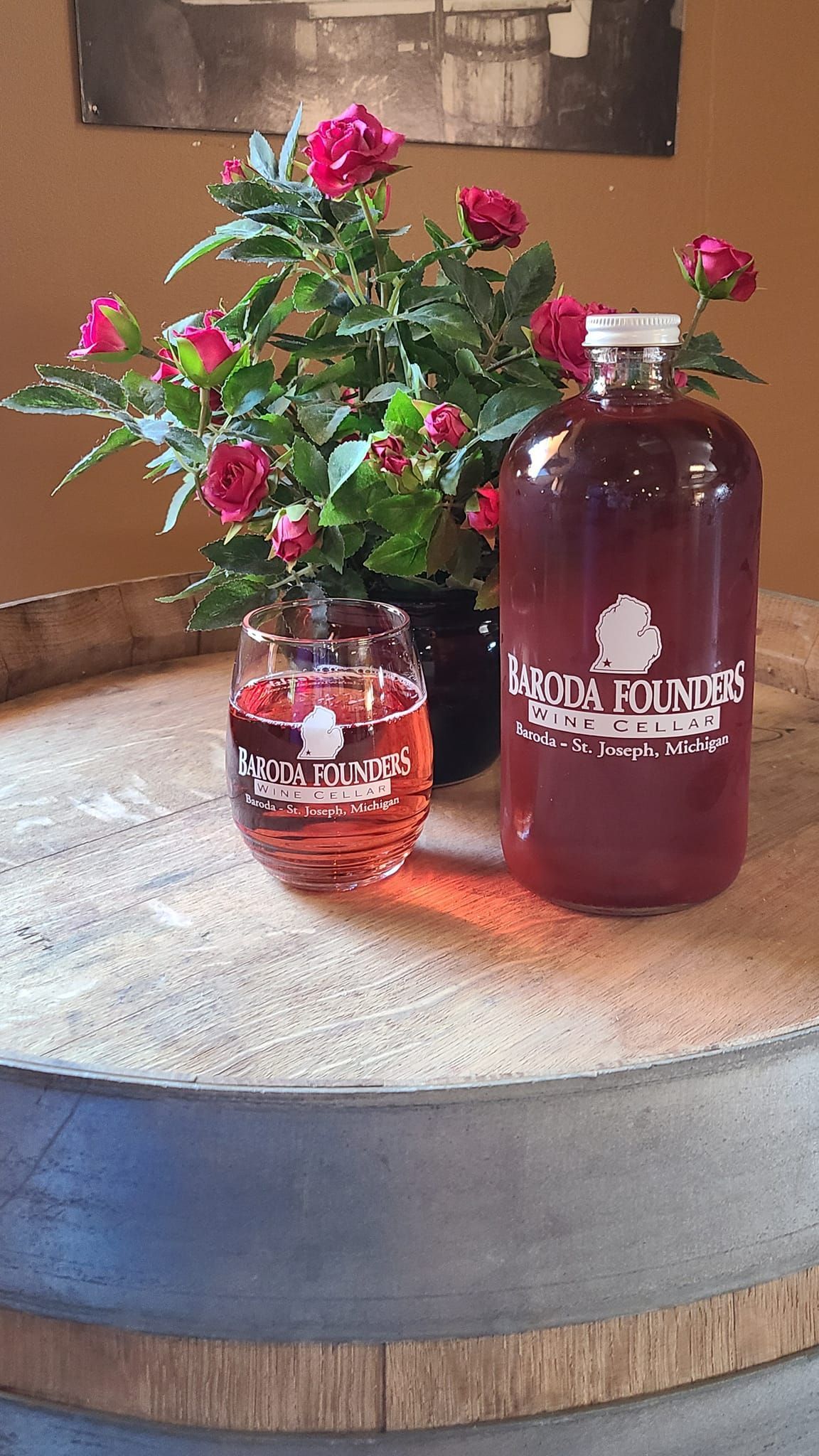 A bottle of wine is sitting on a table next to a vase of flowers.