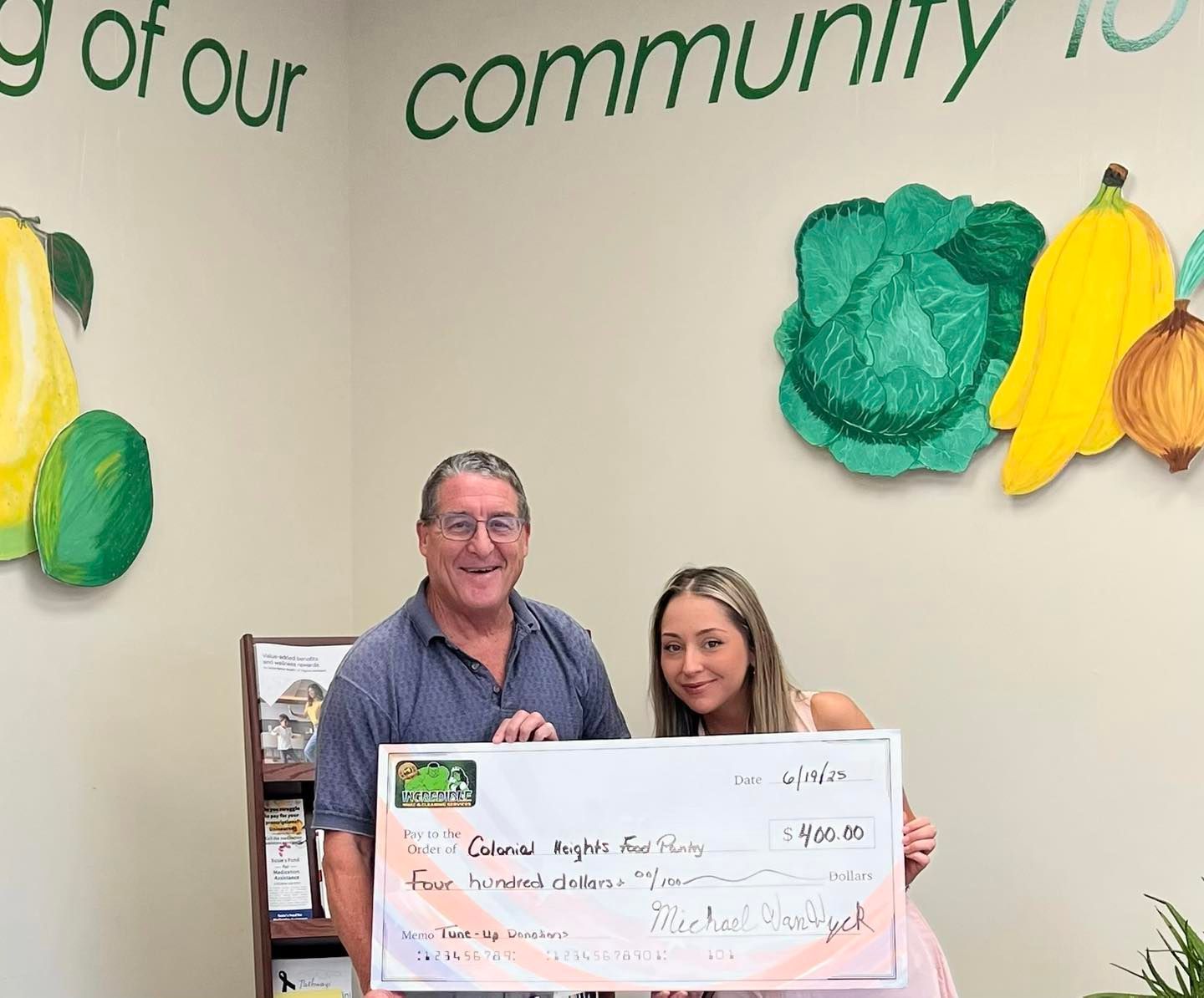 A man and a woman are holding a check in front of a wall.