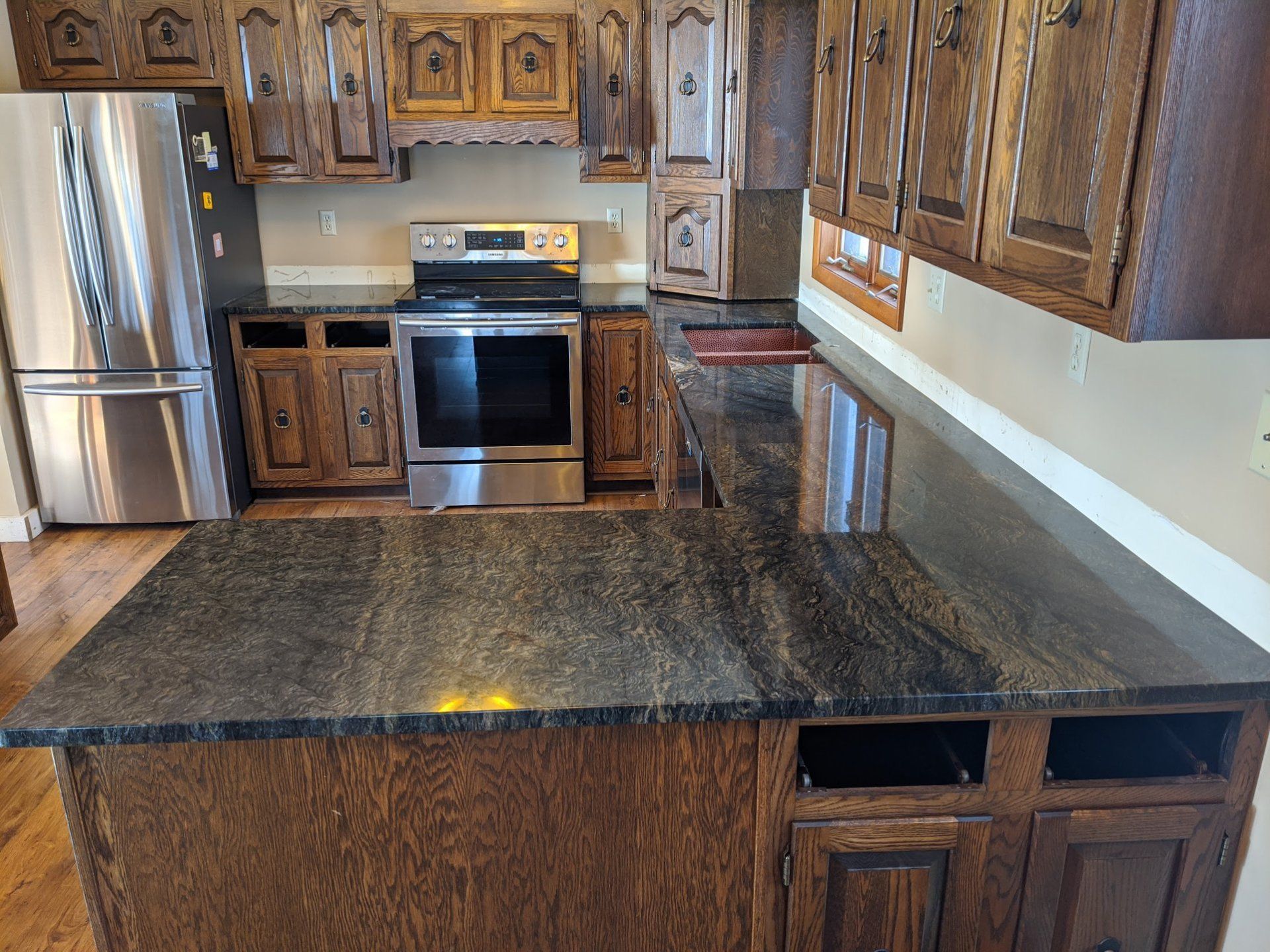 Kitchen with dark wood cabinets and dark granite countertops; stainless steel appliances.