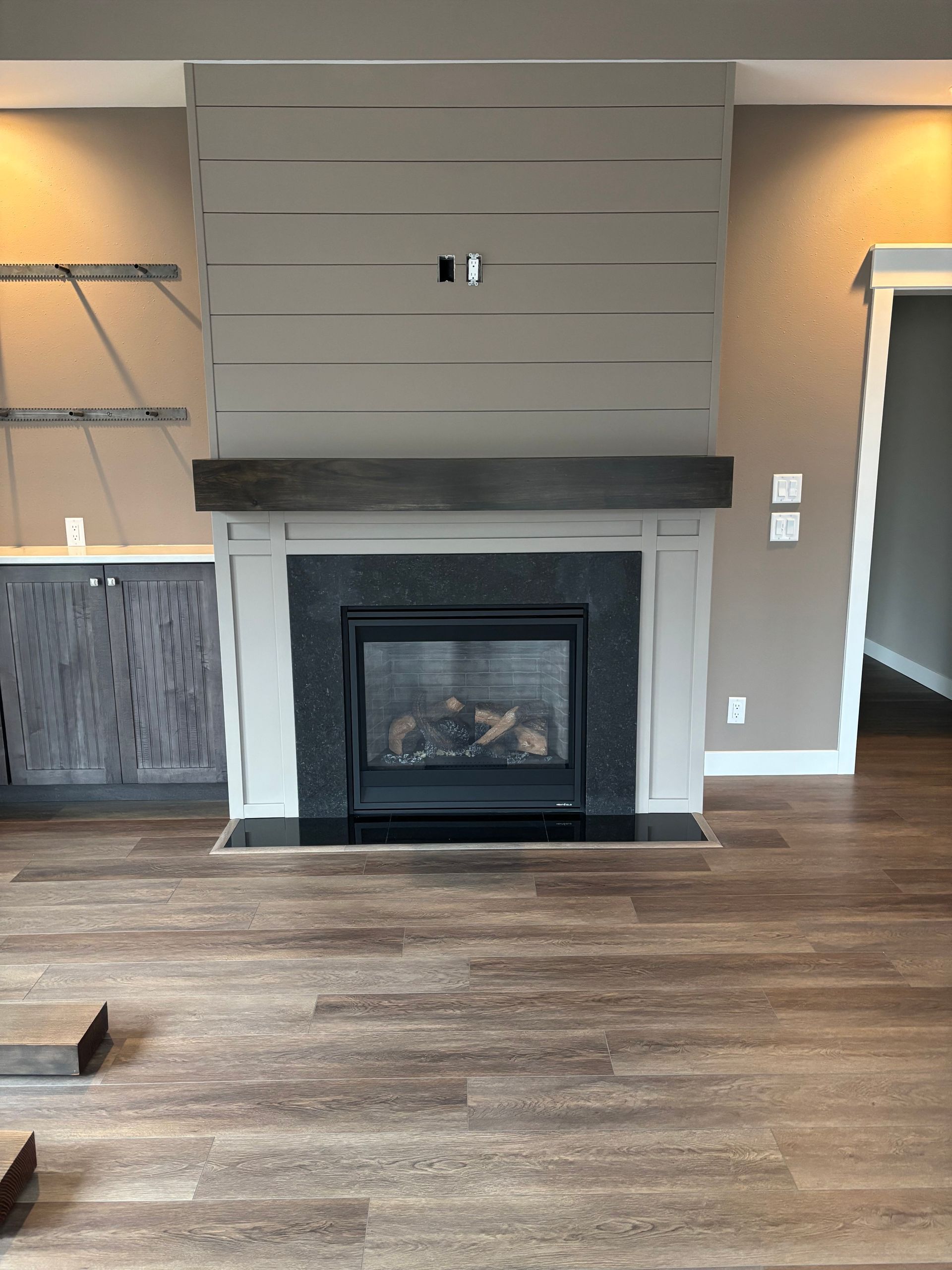 Empty living room with a modern fireplace and gray accent wall on wood floors
