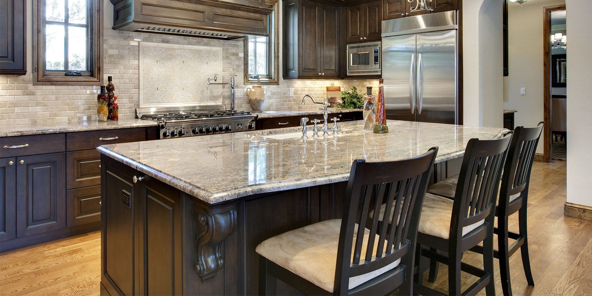 Kitchen with dark cabinetry, granite countertops, and island with bar stools.
