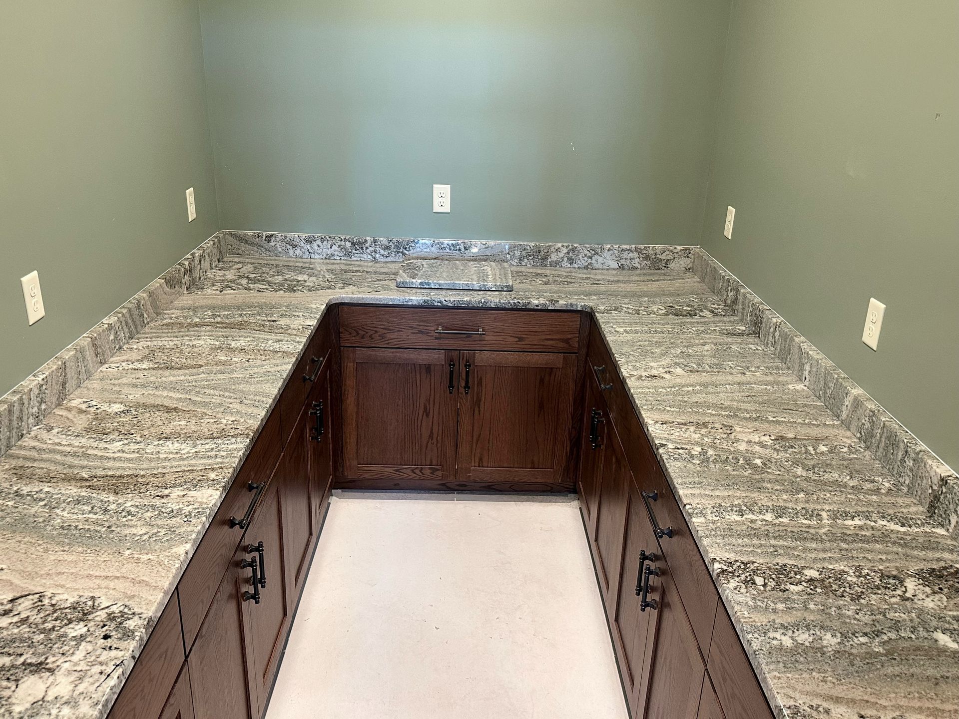 A kitchen pantry with granite countertop and wooden cabinets