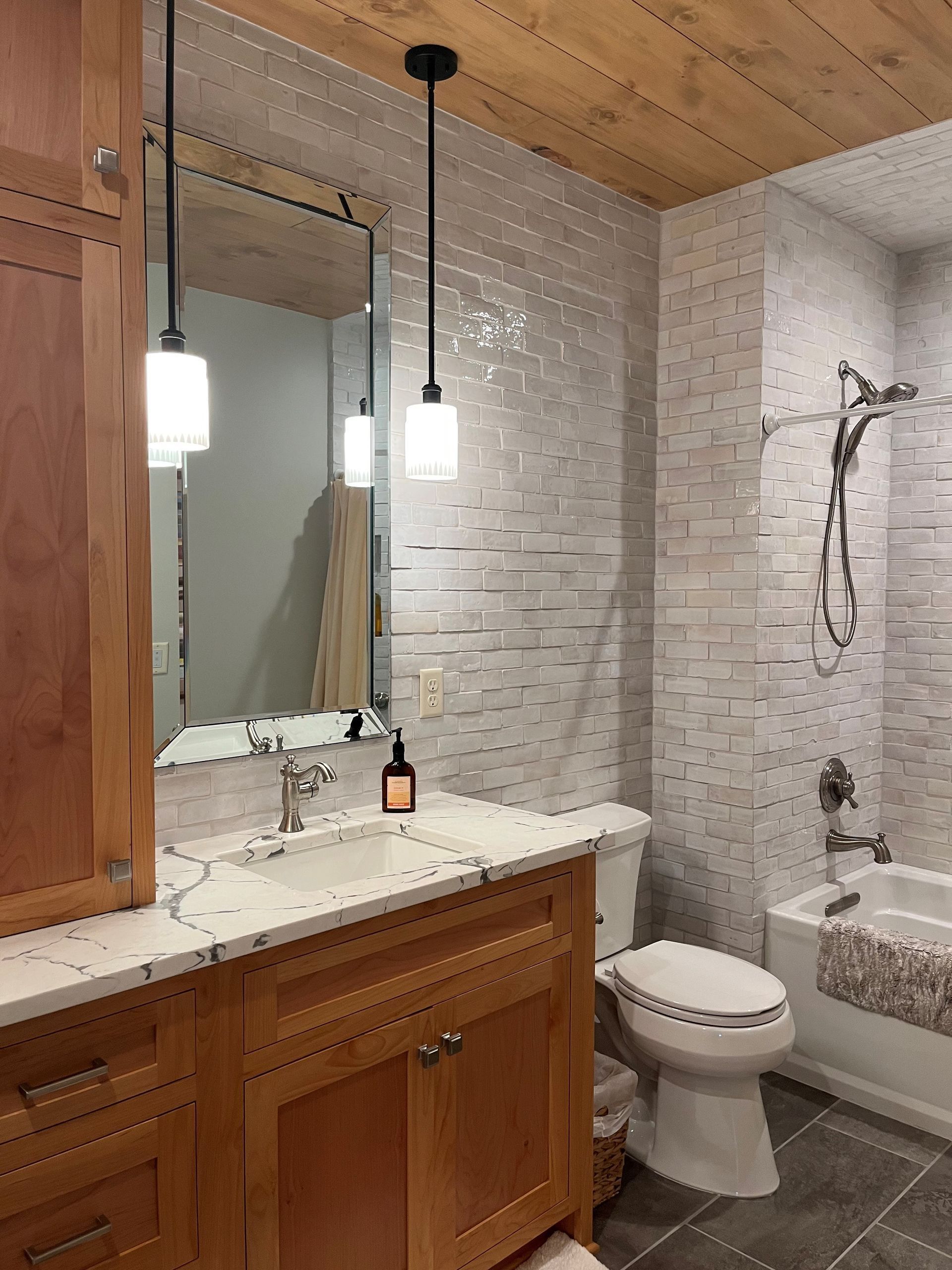 a bathroom with a toilet , sink , mirror and tub .