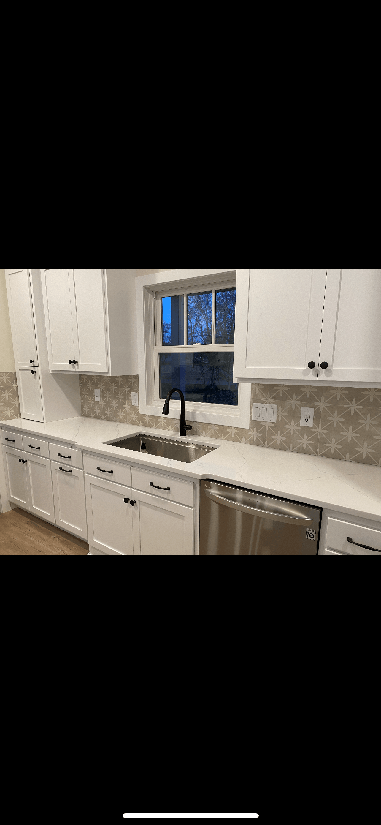 Kitchen sink with window, white cabinets.