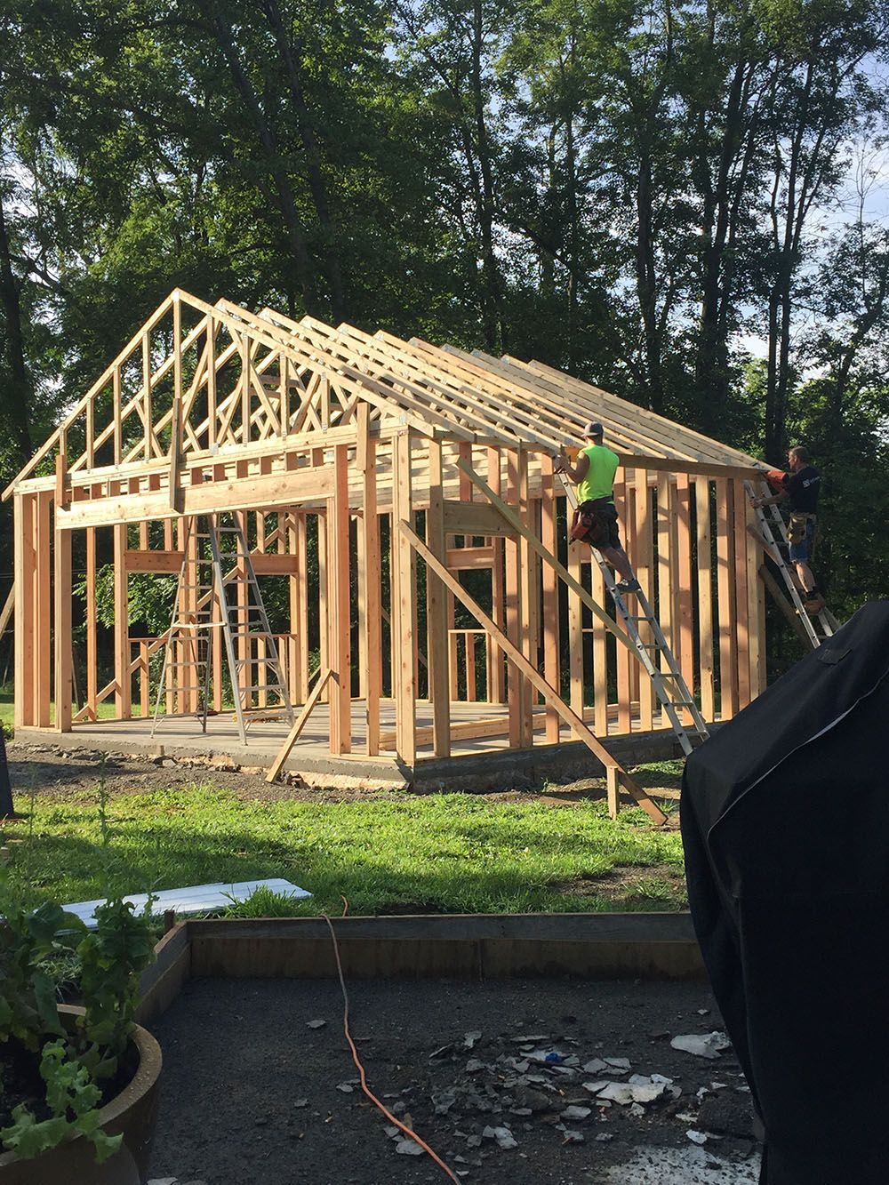 A man is standing on a ladder in front of a building under construction.