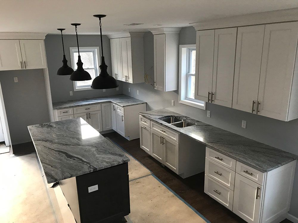 A kitchen with white cabinets and granite counter tops