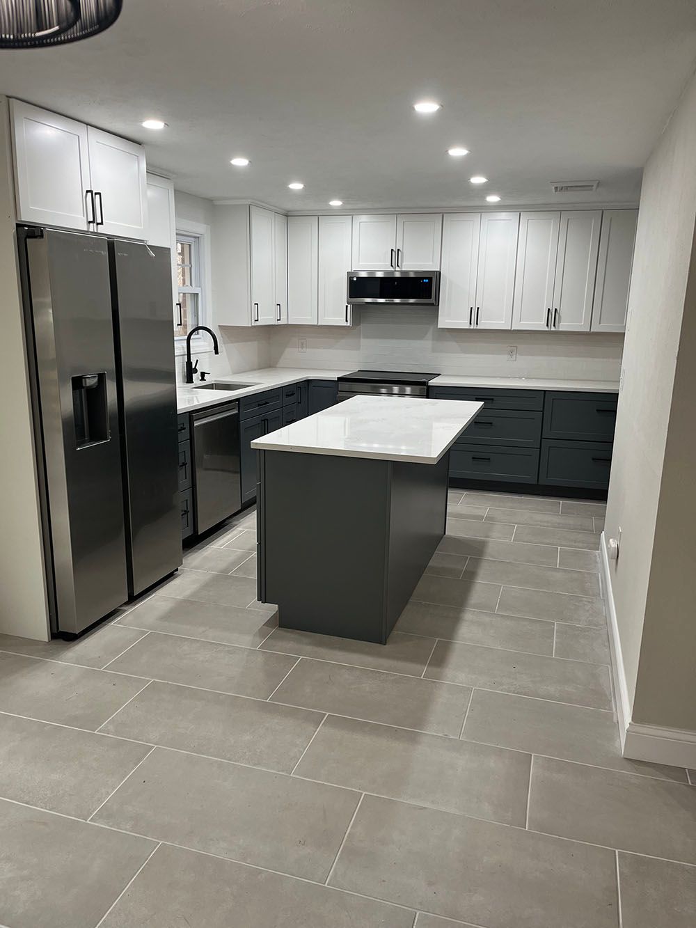 A kitchen with stainless steel appliances and a large island in the middle.