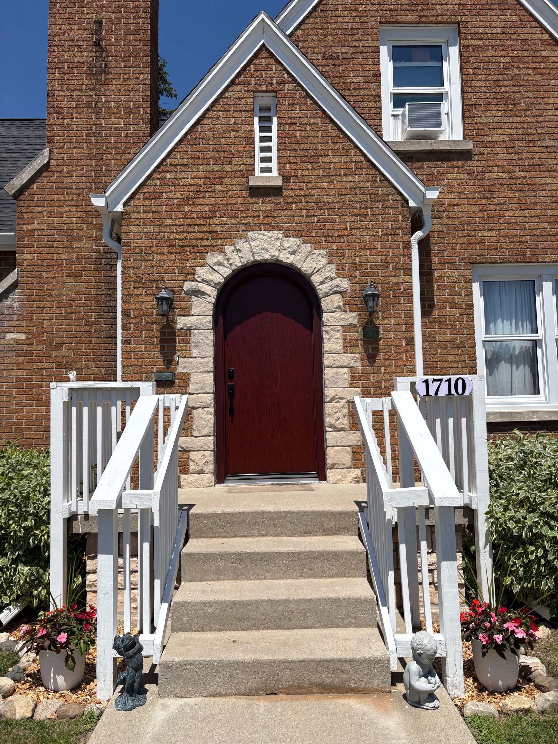 Arched red wooden door set in a brick wall with stone trim and lanterns on both sides