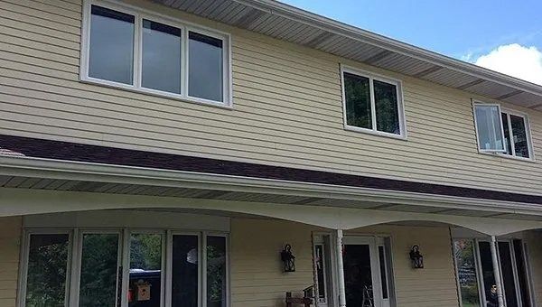 Two-story beige house with multiple windows and a covered porch.