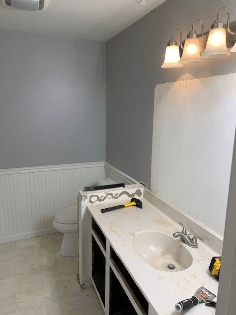Bathroom remodel in progress; grey and white walls, unfinished vanity, and toilet visible.