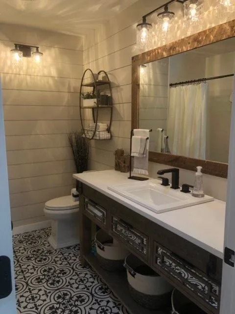 Rustic bathroom with white shiplap walls, patterned tile floor, and a wooden vanity.