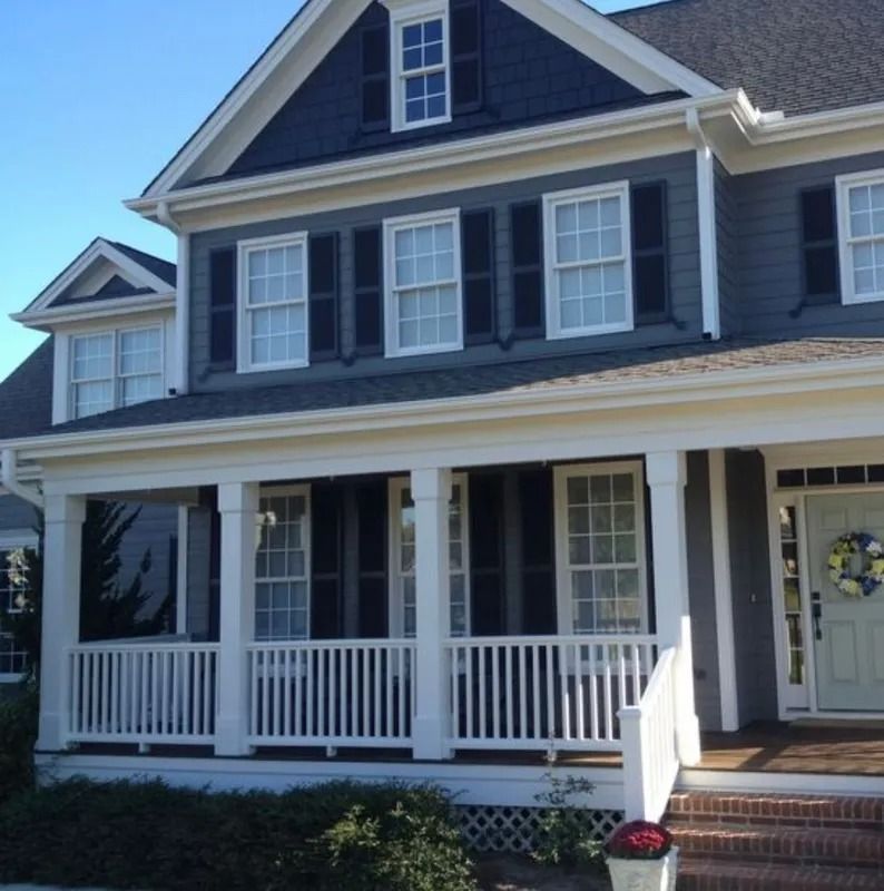Blue and white two-story house with a porch, black shutters, and a front door with a wreath.