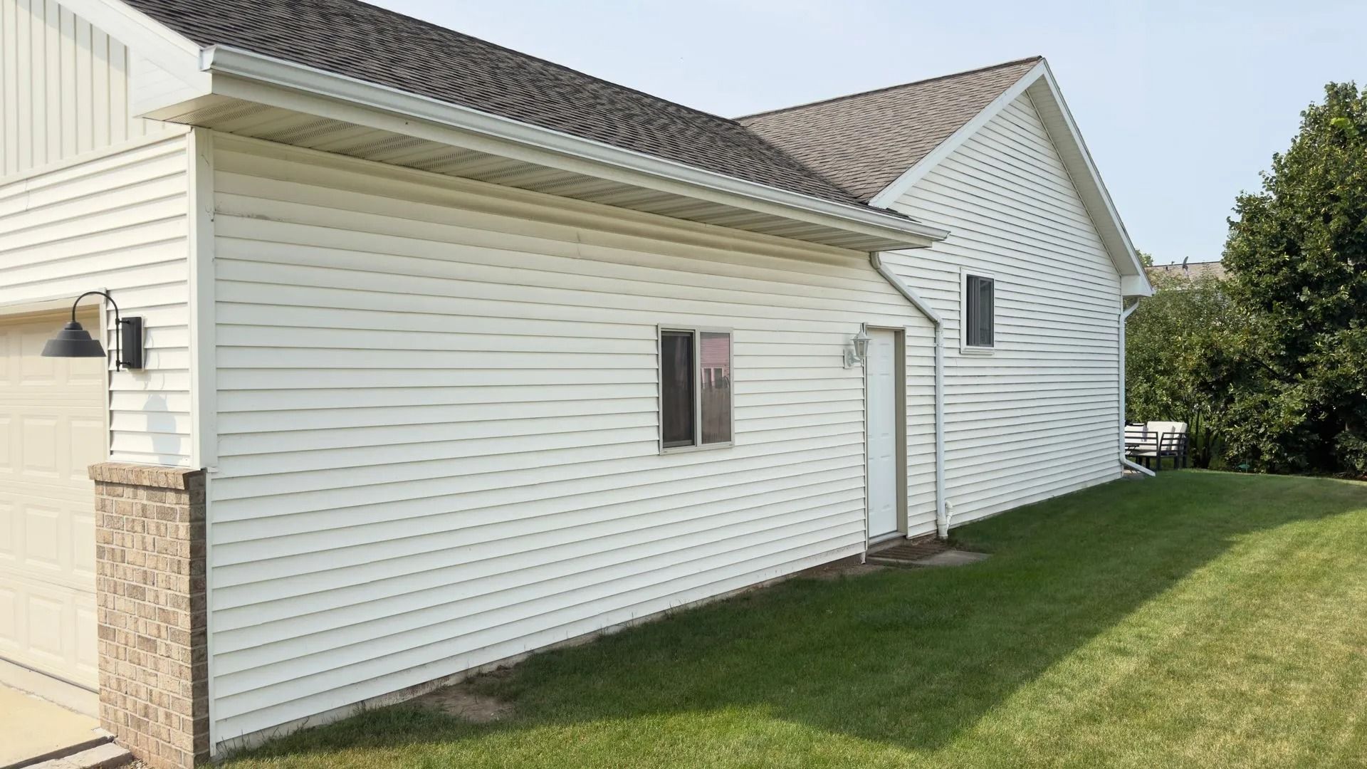 White-sided building with dark roof and green lawn on a sunny day.