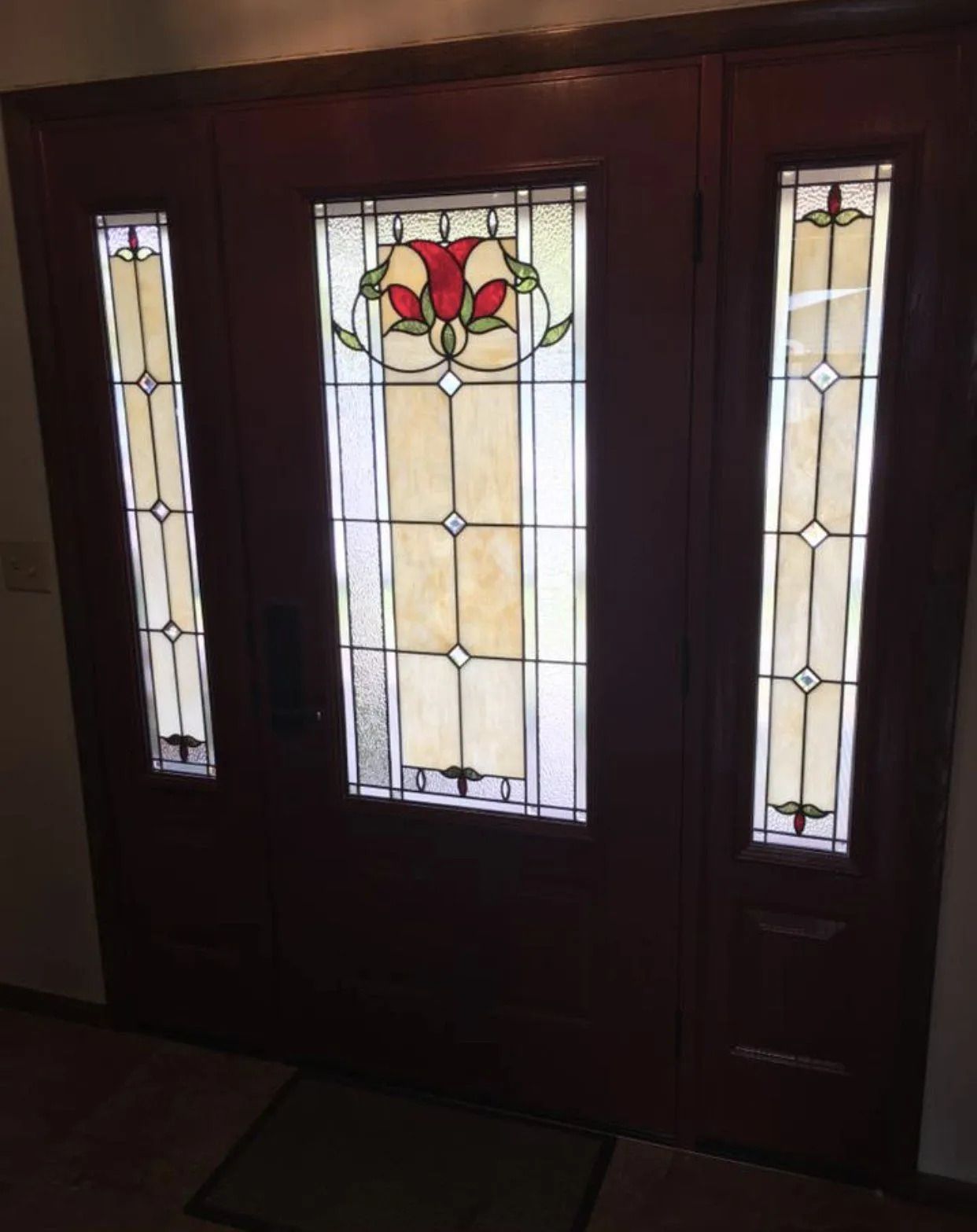 Dark wood front door with stained glass panels. Red flower design, cream and clear glass.