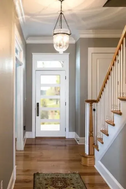 Entryway with a glass-paned door, hardwood floors, and a staircase. A chandelier hangs from the ceiling.