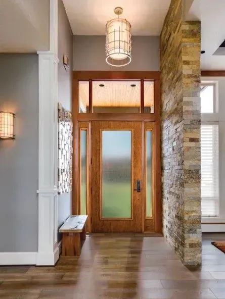 Entryway with wooden door, stone wall accent, pendant light, and bench.