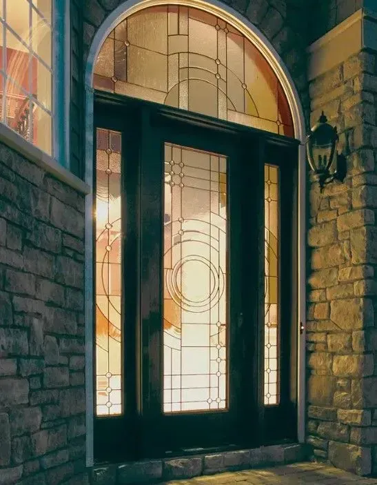 Dark wood front door with arched glass transom, set in stone wall.